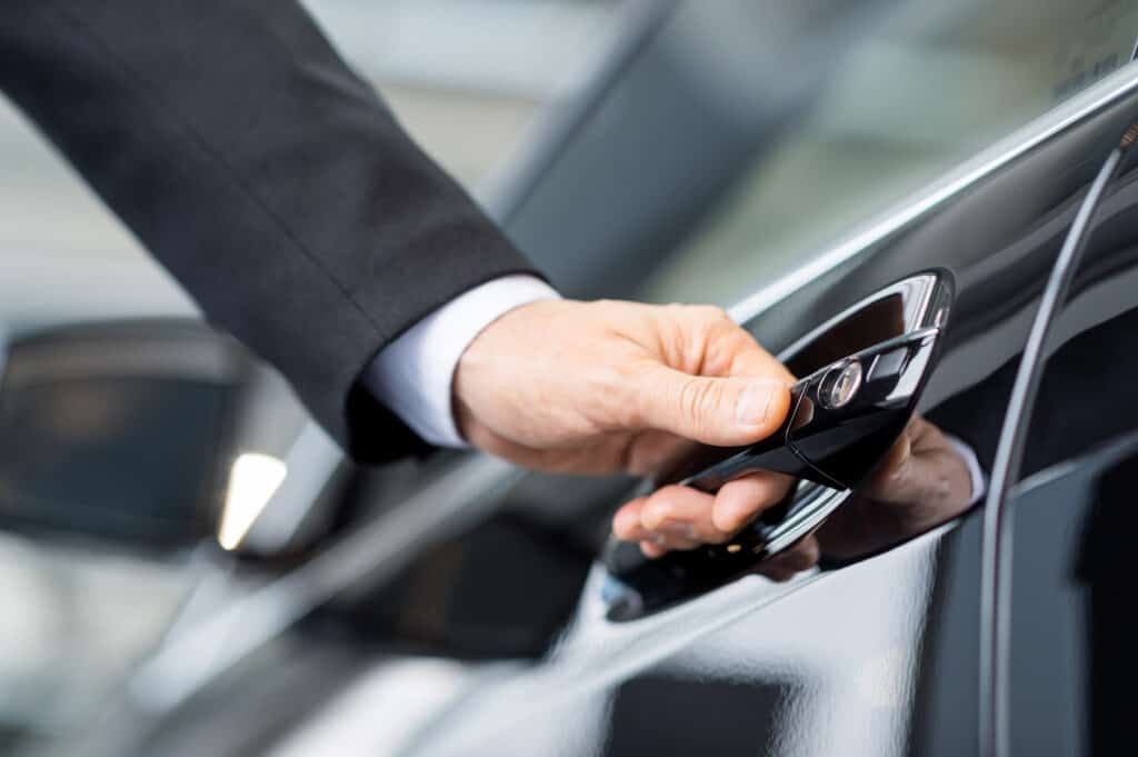 Professional chauffeur opening luxury car door, highlighting safety, discretion, and protection standards in Ireland