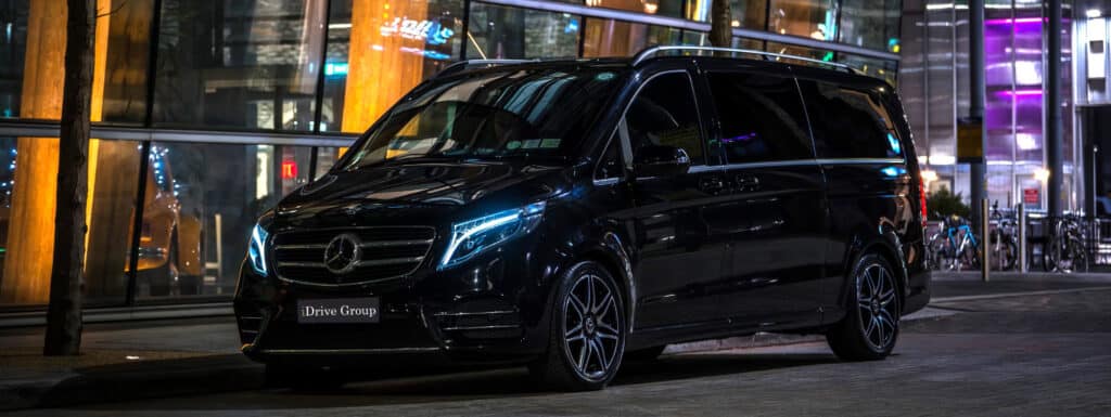 Black & white Mercedes V-Class luxury van driving through the streets of Dublin, ideal for group travel and executive chauffeur hire
