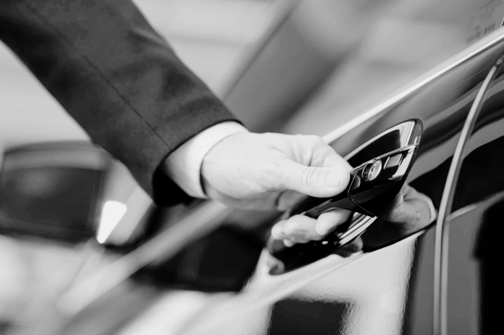 Professional chauffeur opening luxury car door, highlighting safety, discretion, and protection standards in Ireland